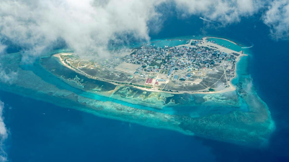 Stunning aerial view of a tropical island surrounded by turquoise sea, showcasing vibrant coastal town.