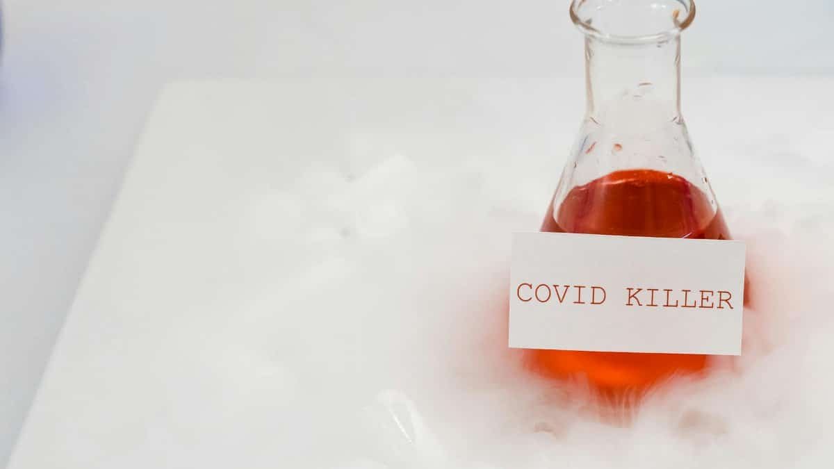 Erlenmeyer flask with red liquid labeled 'COVID KILLER' surrounded by fog in a laboratory setting.