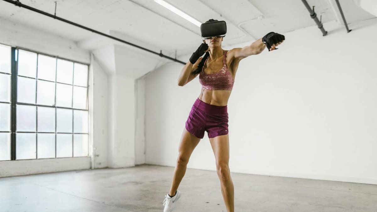 A woman engaging in a workout session using a VR headset indoors, promoting fitness and technology synergy.