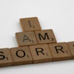 Wooden Scrabble tiles arranged to say 'I Am Sorry' on a clean white background, conveying a message of apology.
