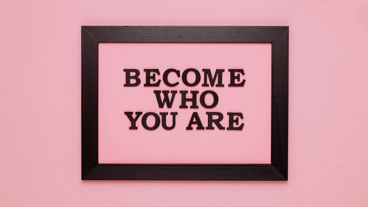 Inspiring quote 'Become Who You Are' framed on a vibrant pink wall, perfect for encouragement.