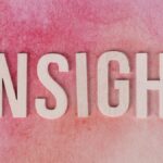 Wooden letters spelling INSIGHT on a pink watercolor background.