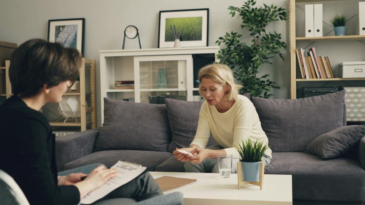 A professional therapy session with a therapist and patient in a modern living room setting.