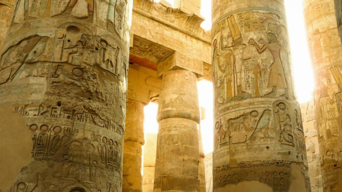Close-up of ancient Egyptian columns adorned with hieroglyphics and carvings at a historical temple site.