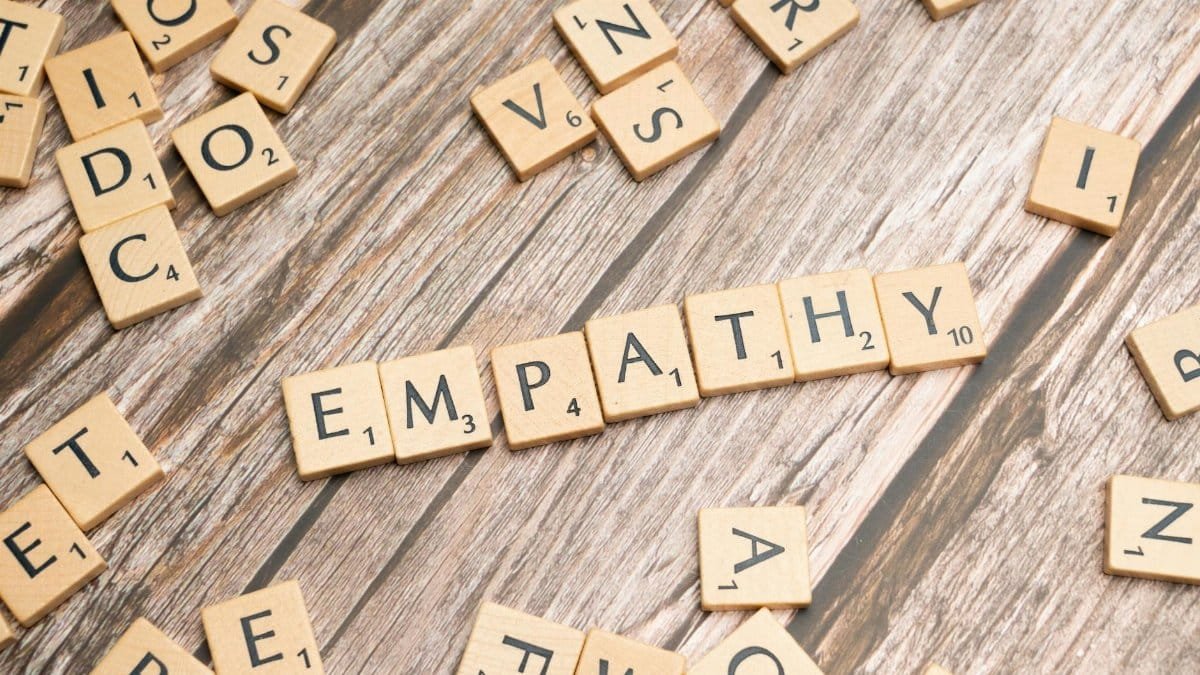 Wooden letter tiles spelling 'empathy' on a wooden background conveying connection.