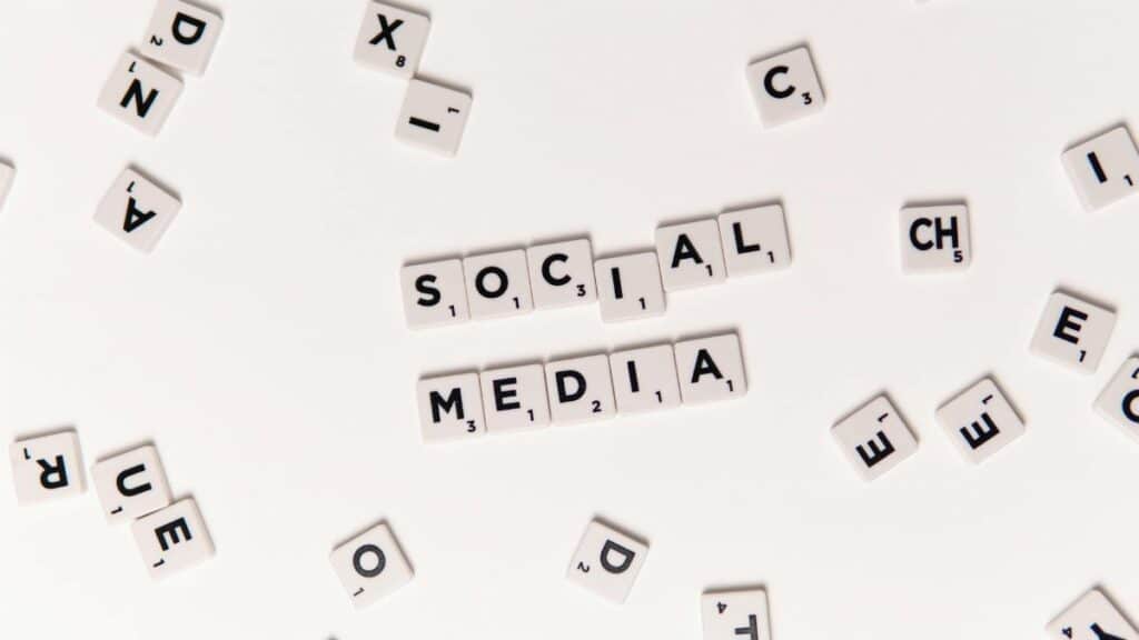 Flat lay of letter tiles spelling Social Media with scattered white tiles on a surface.
