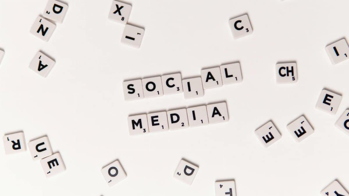 Flat lay of letter tiles spelling Social Media with scattered white tiles on a surface.