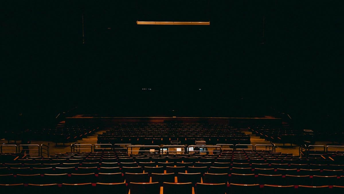 A dark and empty auditorium in Fortaleza, featuring rows of chairs and a stage.
