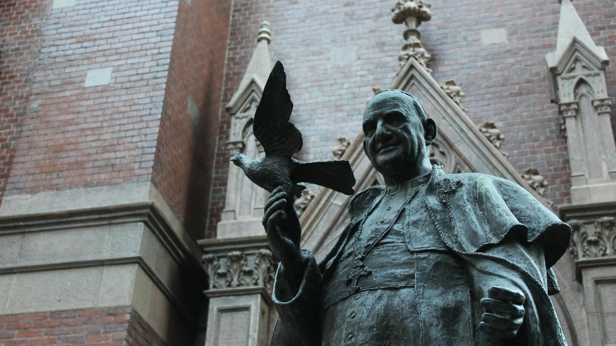 Bronze statue of Pope John XXIII with a dove, against a historic brick wall in İstanbul, Turkey.