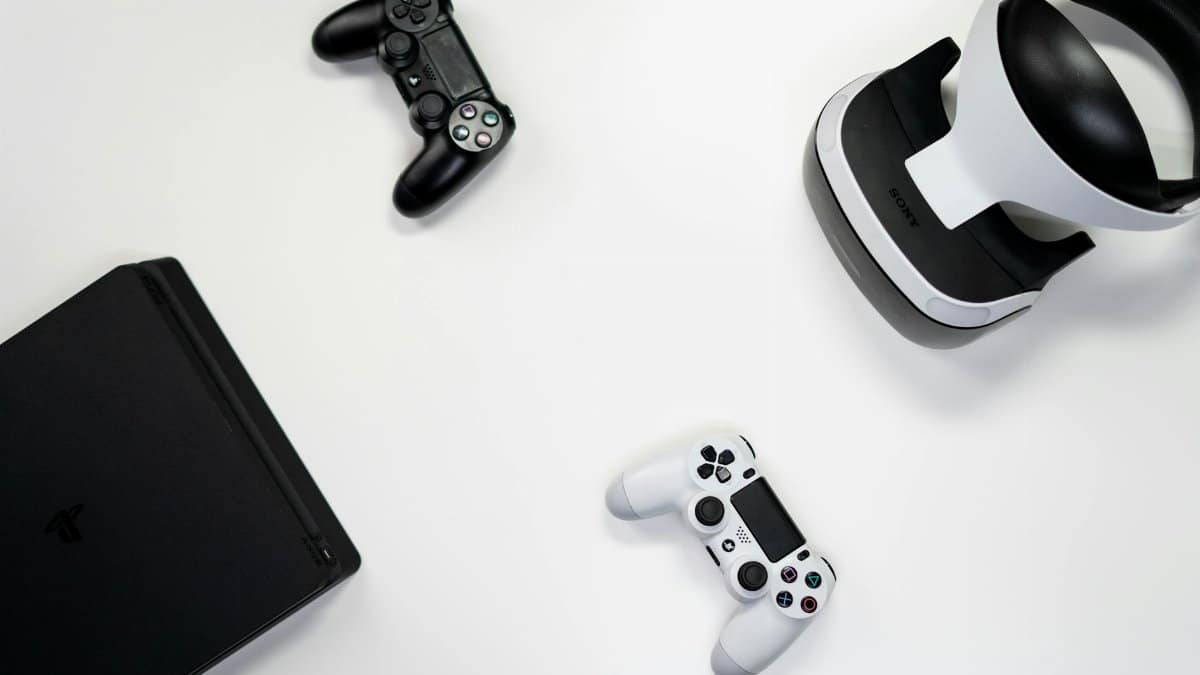 Flat lay of gaming console, controllers, and VR headset on a white background.