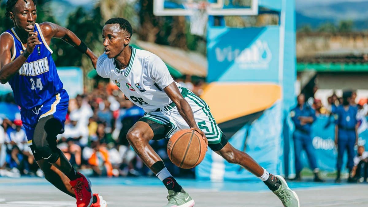 Two players in a competitive basketball game on an outdoor court during the day.