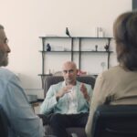 Therapist holding a session with an elderly couple discussing mental health in a professional office setting.