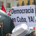 A vibrant street protest advocating for democracy in Cuba with visible signs.
