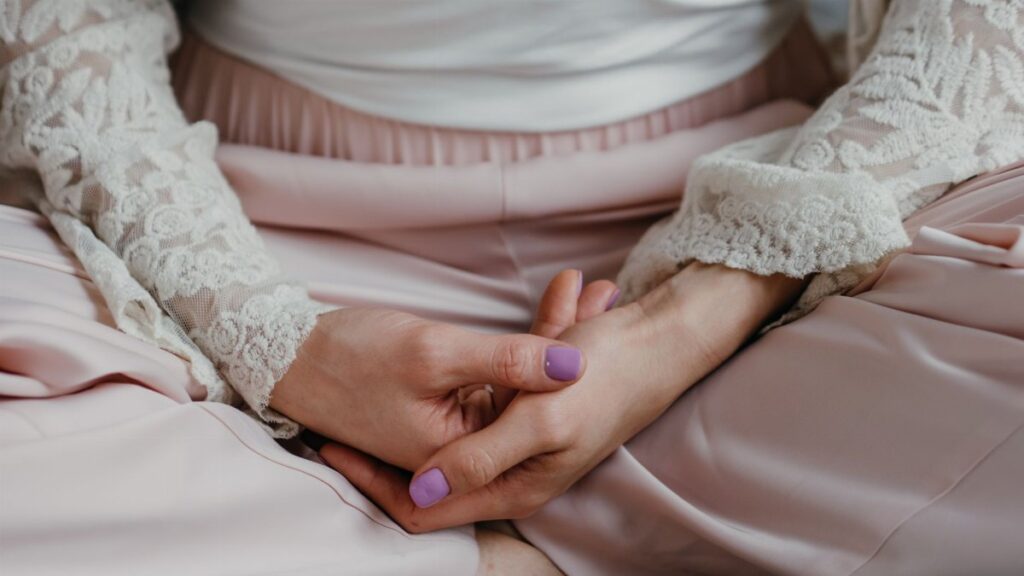 A woman in elegant lace attire practicing meditation in a calm indoor setting.