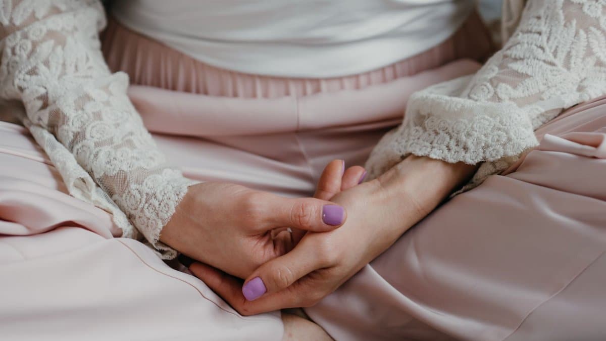 A woman in elegant lace attire practicing meditation in a calm indoor setting.