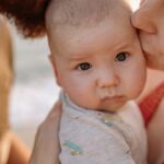A tender moment of parents kissing their baby, highlighting love and family bonds.