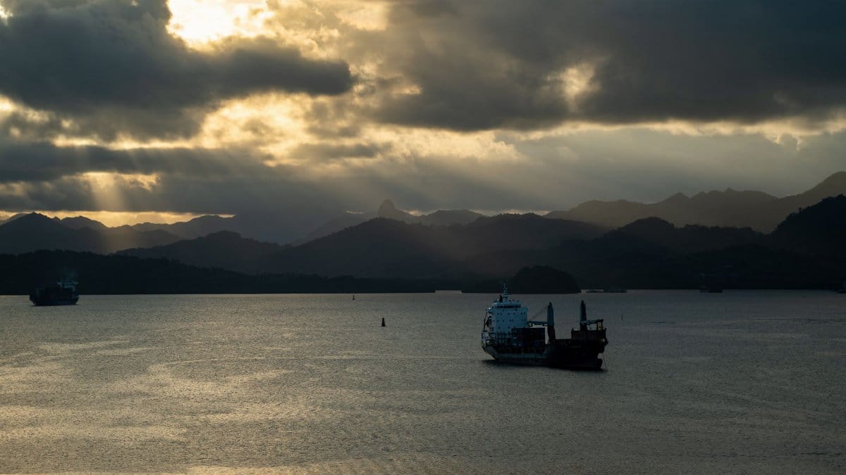 Stunning view of a cargo ship in Fiji at sunset with majestic mountains.