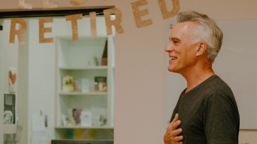 A happy retiree celebrates his retirement with a heartfelt smile indoors.