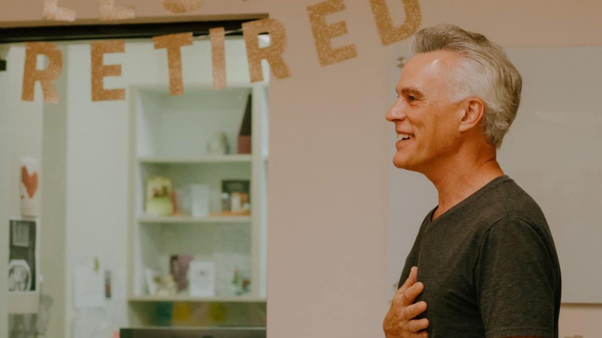 A happy retiree celebrates his retirement with a heartfelt smile indoors.
