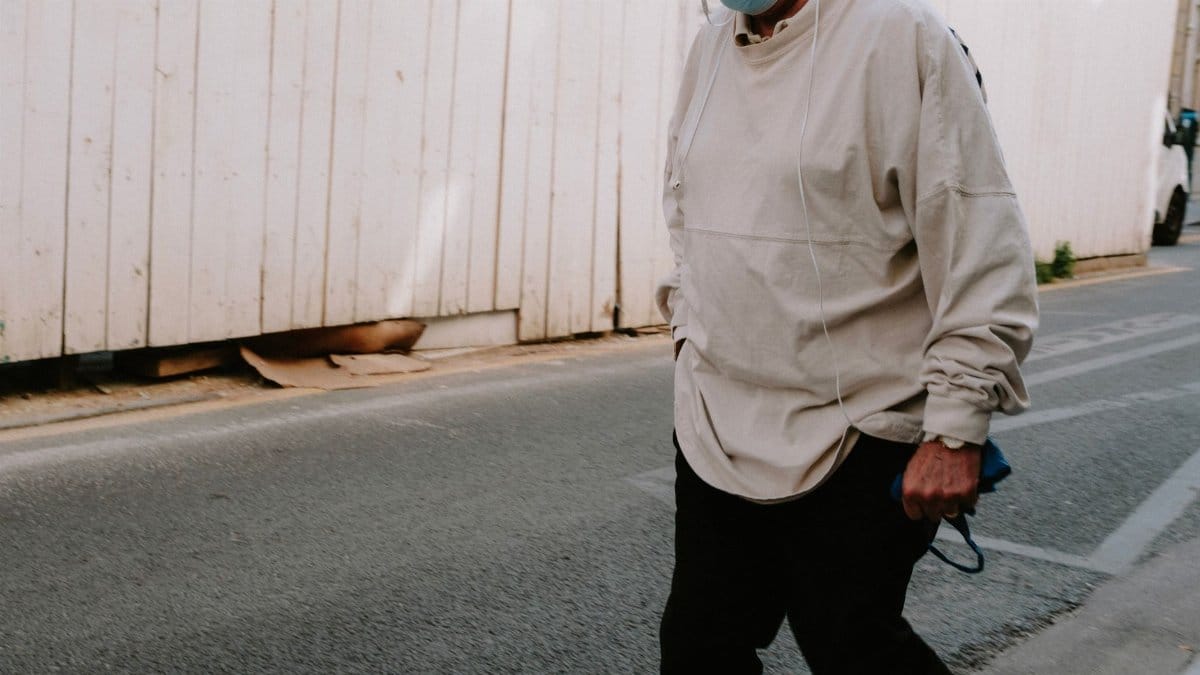 Unrecognizable person wearing a face mask walking on a street, embracing the new normal.