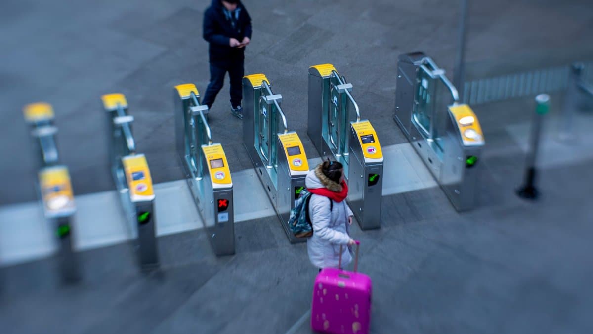 Commuters with luggage pass through ticket barriers at a station in Den Haag, Netherlands.
