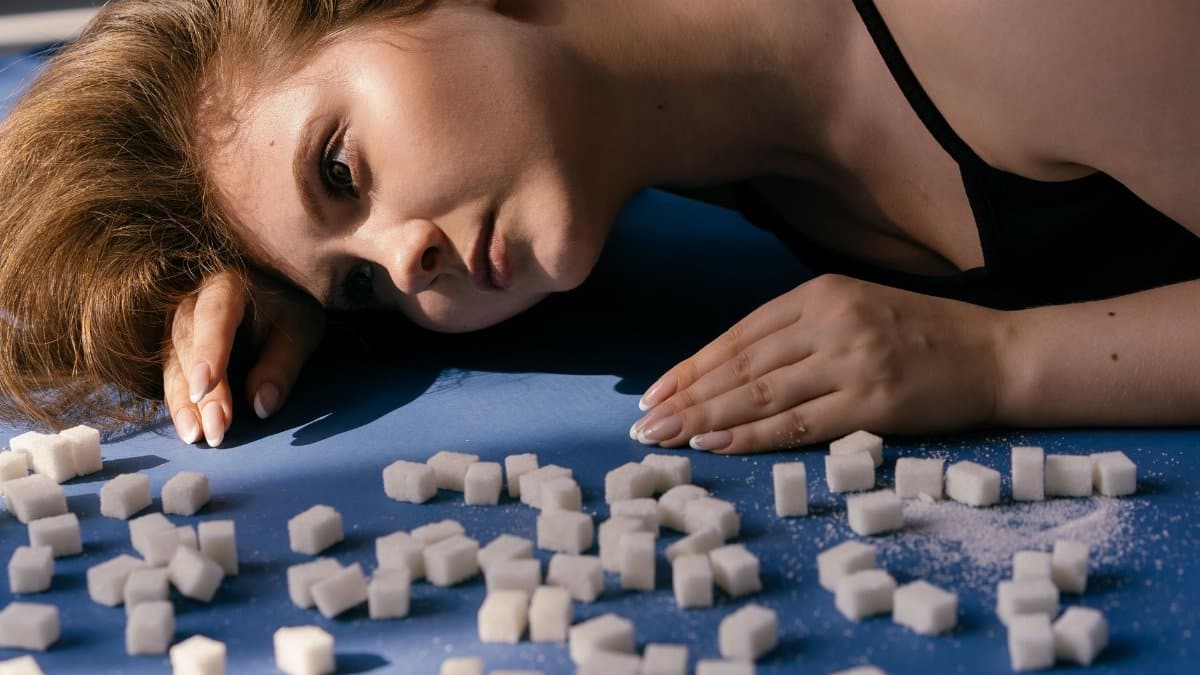 A thoughtful woman surrounded by sugar cubes symbolizes the struggle with unhealthy eating and diabetes.