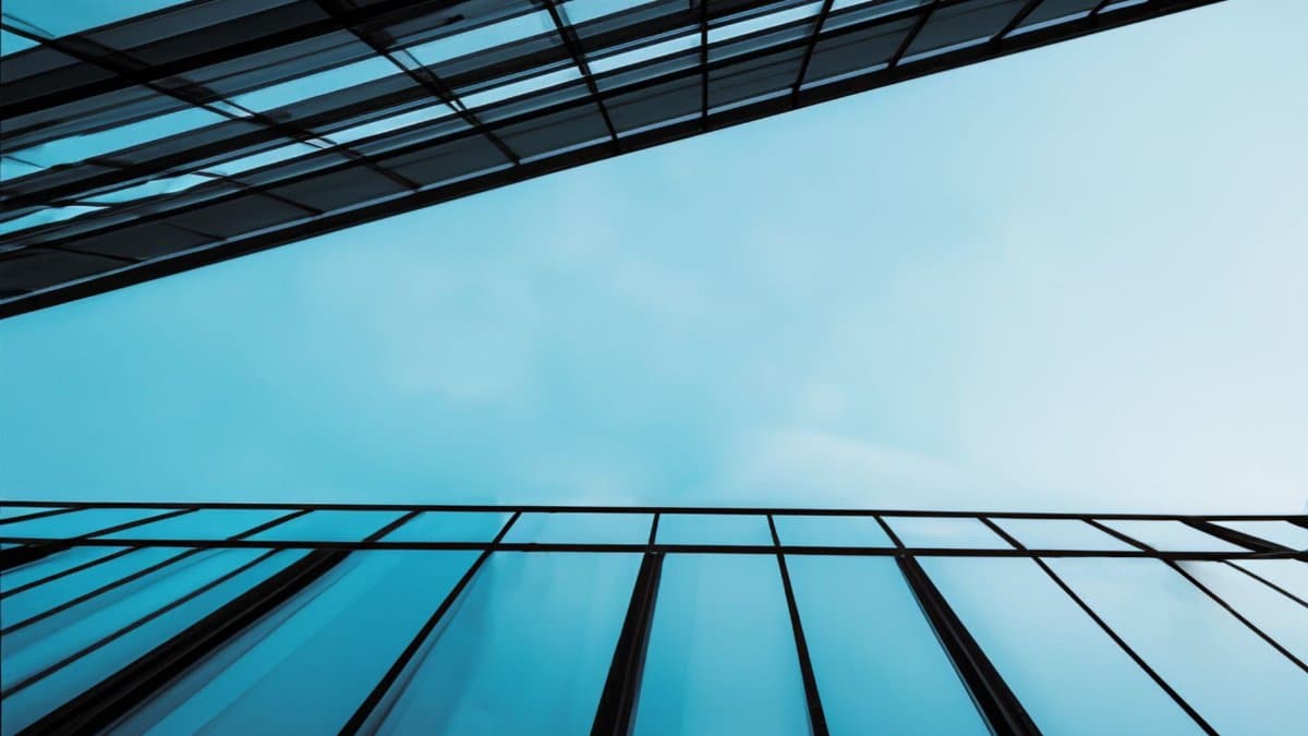 Striking low-angle shot of glass buildings against a clear blue sky, showcasing modern architectural design.