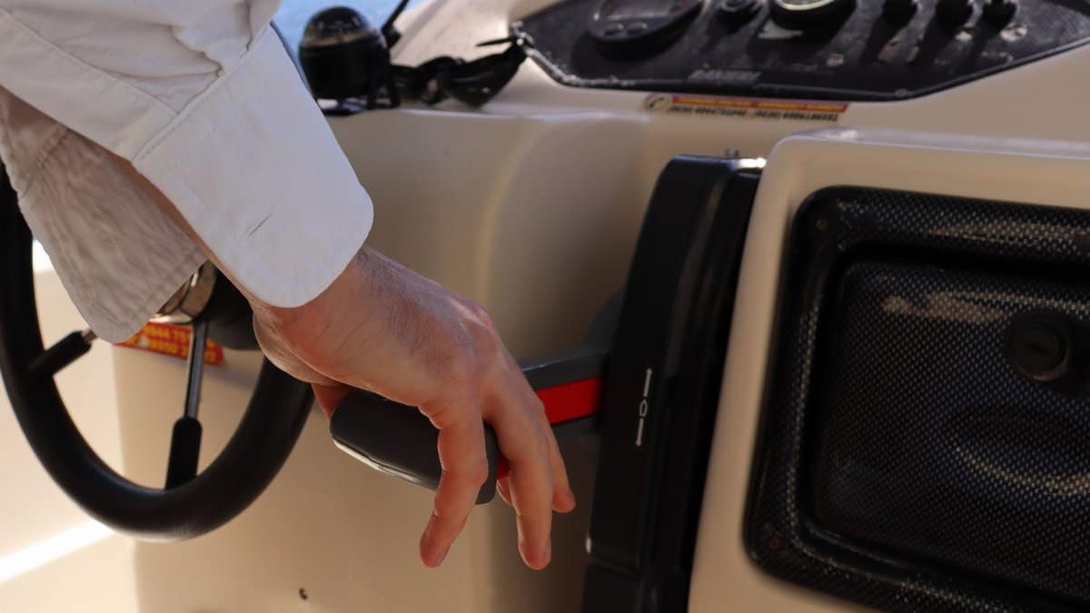 A person adjusting the throttle on a boat control panel, highlighting action and navigation.