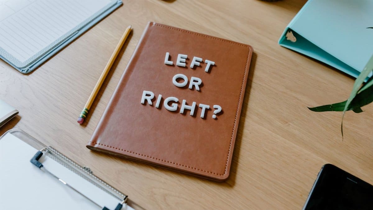 Top-down view of a desk with a notebook asking 'Left or Right?' and various office supplies.