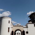 A 20th-century white building with an archway entrance under a clear blue sky.