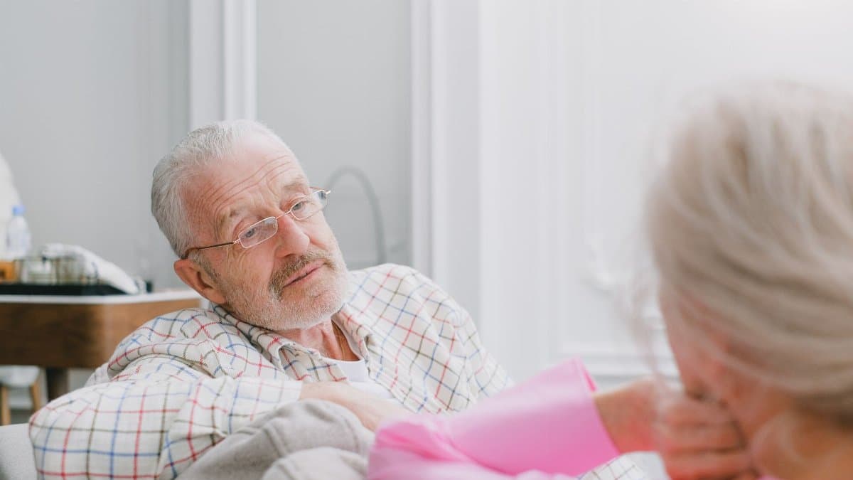 Elderly couple in conversation indoors; relaxed and intimate setting.