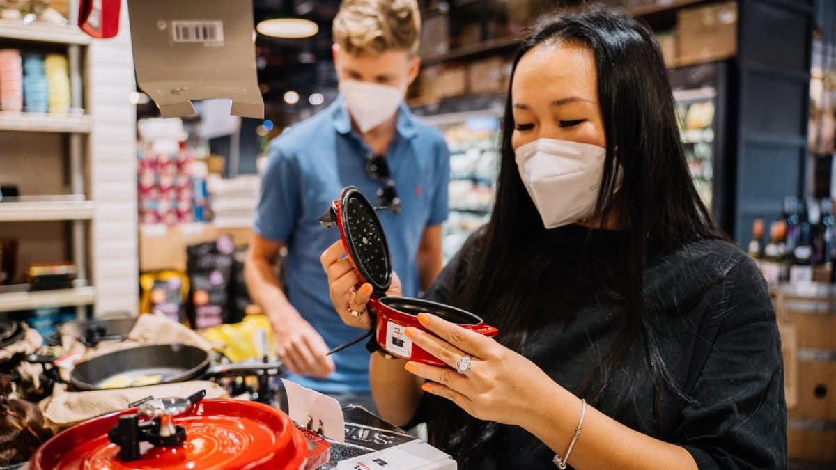 A couple wearing masks shops for kitchenware, exemplifying pandemic precautions.