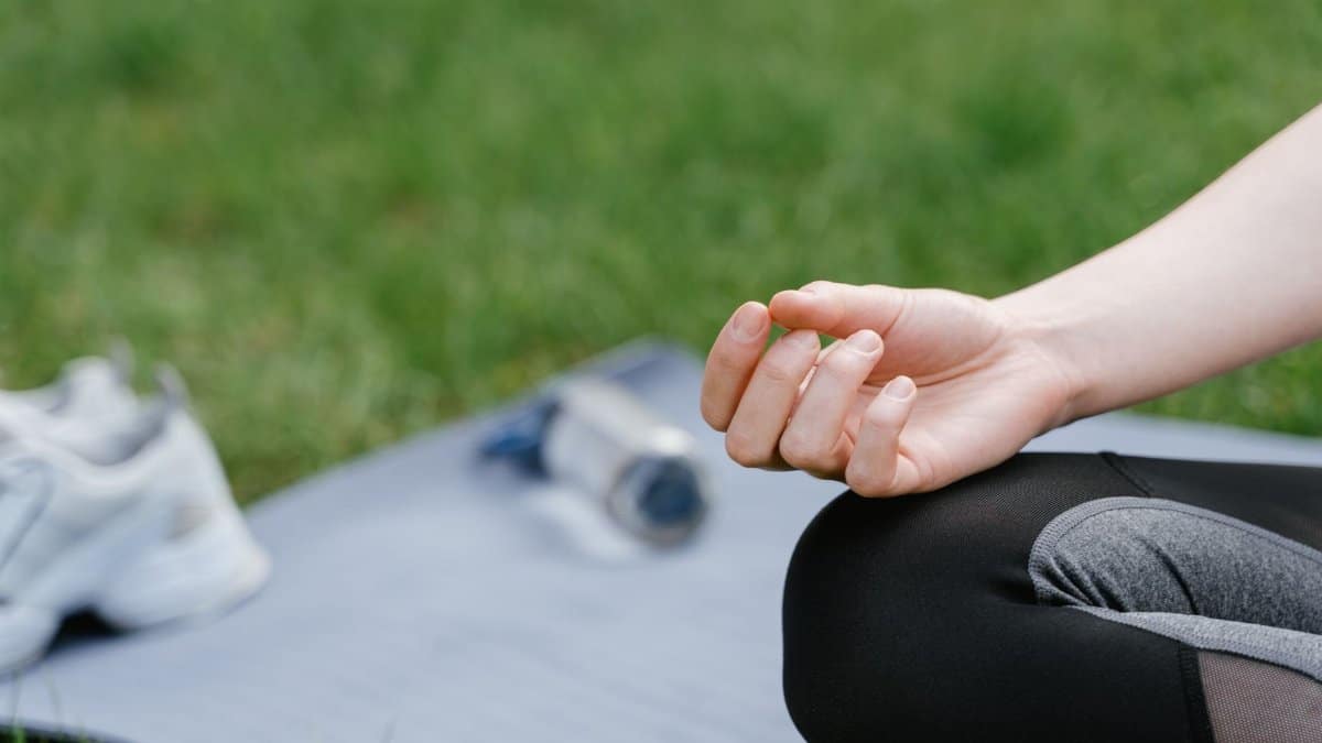 Close-up of a woman meditating outdoors on a mat. Focus on tranquility and mindfulness.