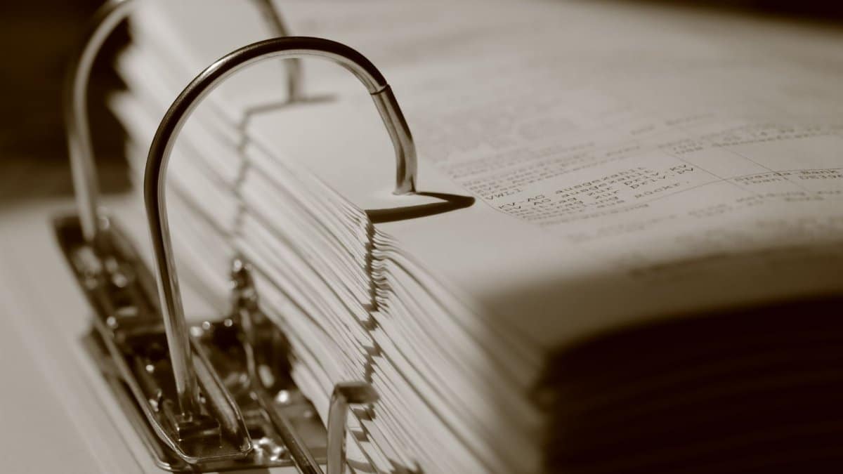 Detailed sepia close-up of a binder filled with documents, emphasizing texture.