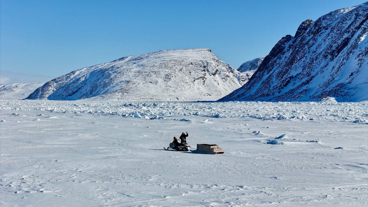 Snowmobile traversing the icy plains with snow-capped mountains in the background, Arctic exploration.