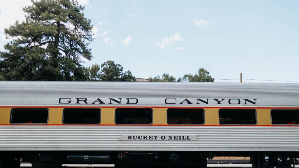 Side view of a vintage Grand Canyon Railway passenger car under a clear sky.