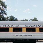 Side view of a vintage Grand Canyon Railway passenger car under a clear sky.