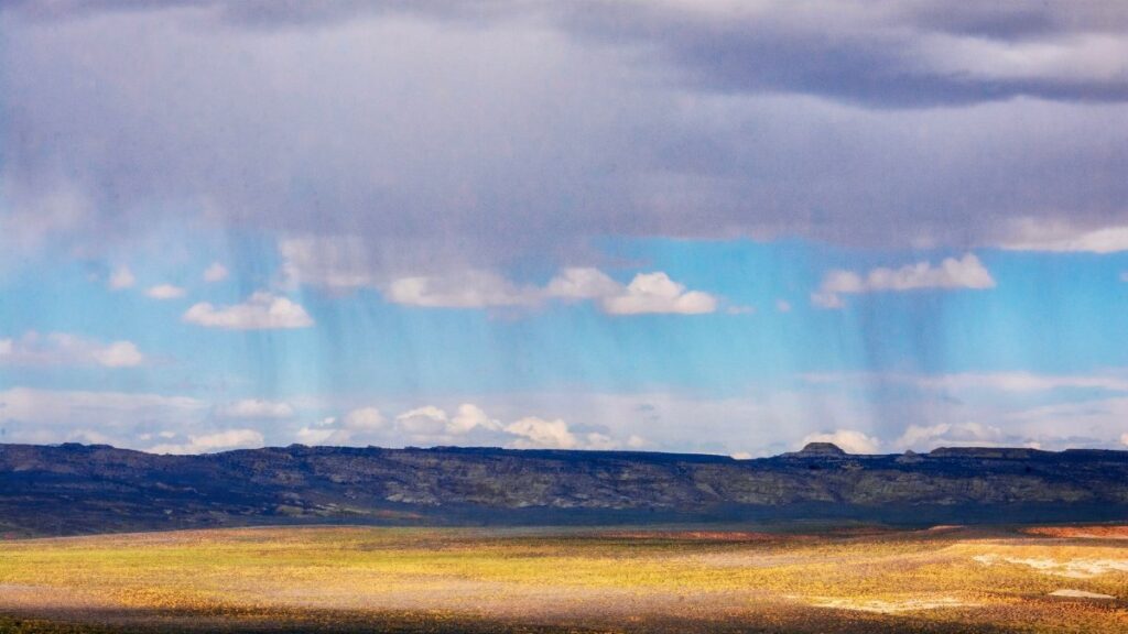 A scenic view of a vast field under a rainy sky in Page, Arizona, highlighting dramatic weather.