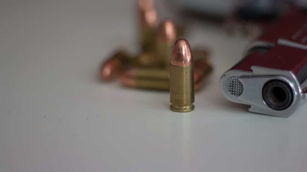 A detailed image of a handgun and multiple bullets on a white background, showing focus on firearm elements.