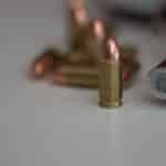A detailed image of a handgun and multiple bullets on a white background, showing focus on firearm elements.