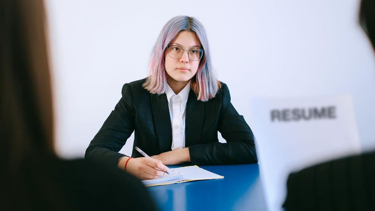A young woman in a suit during a job interview, writing notes.