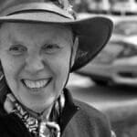 Black and white portrait of a smiling elderly woman wearing a hat, outdoors in Geneva, IL.