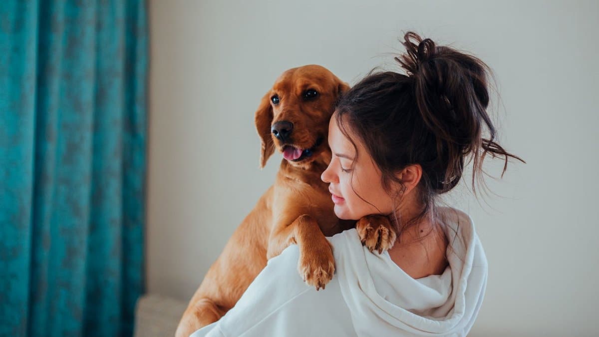 A woman lovingly embraces her dog indoors, showcasing their bond.