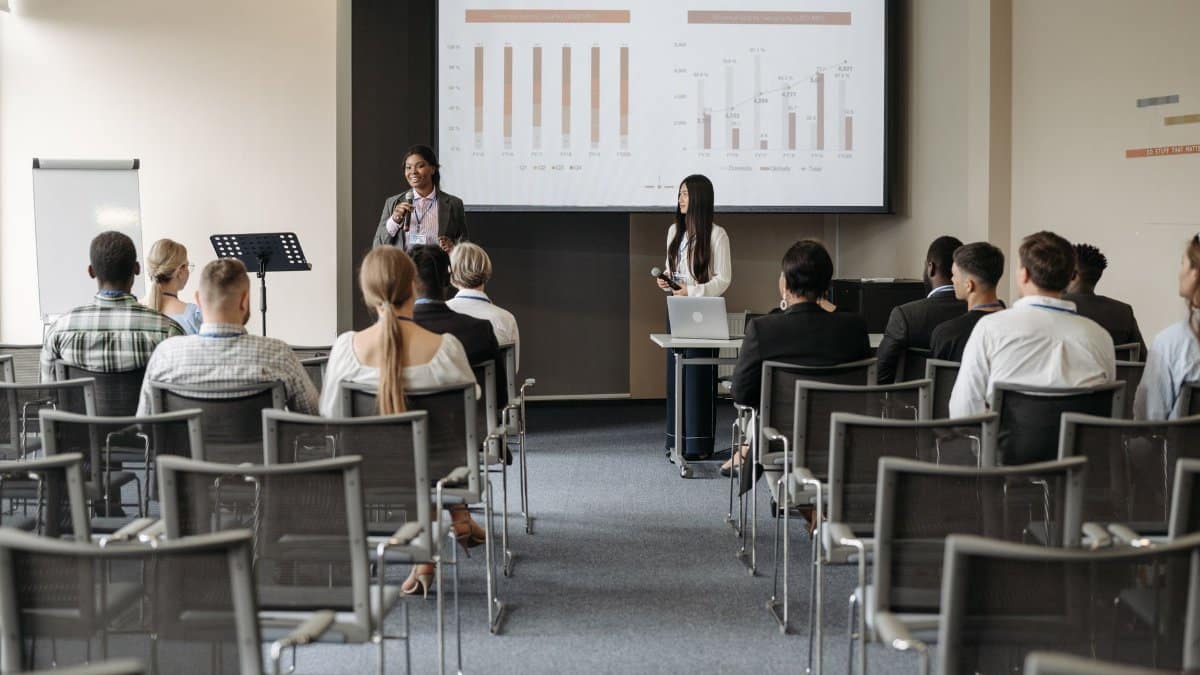 Professional business seminar with audience listening to presenters sharing data insights.