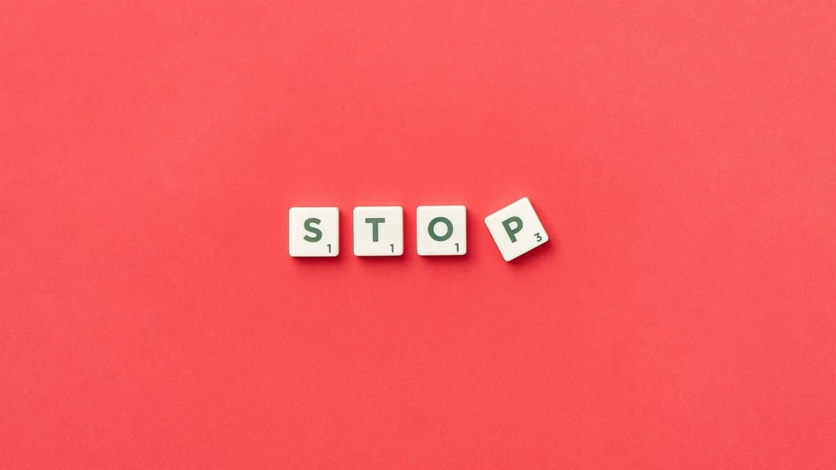 Scrabble tiles spelling 'STOP' on a vivid red background, viewed from above.