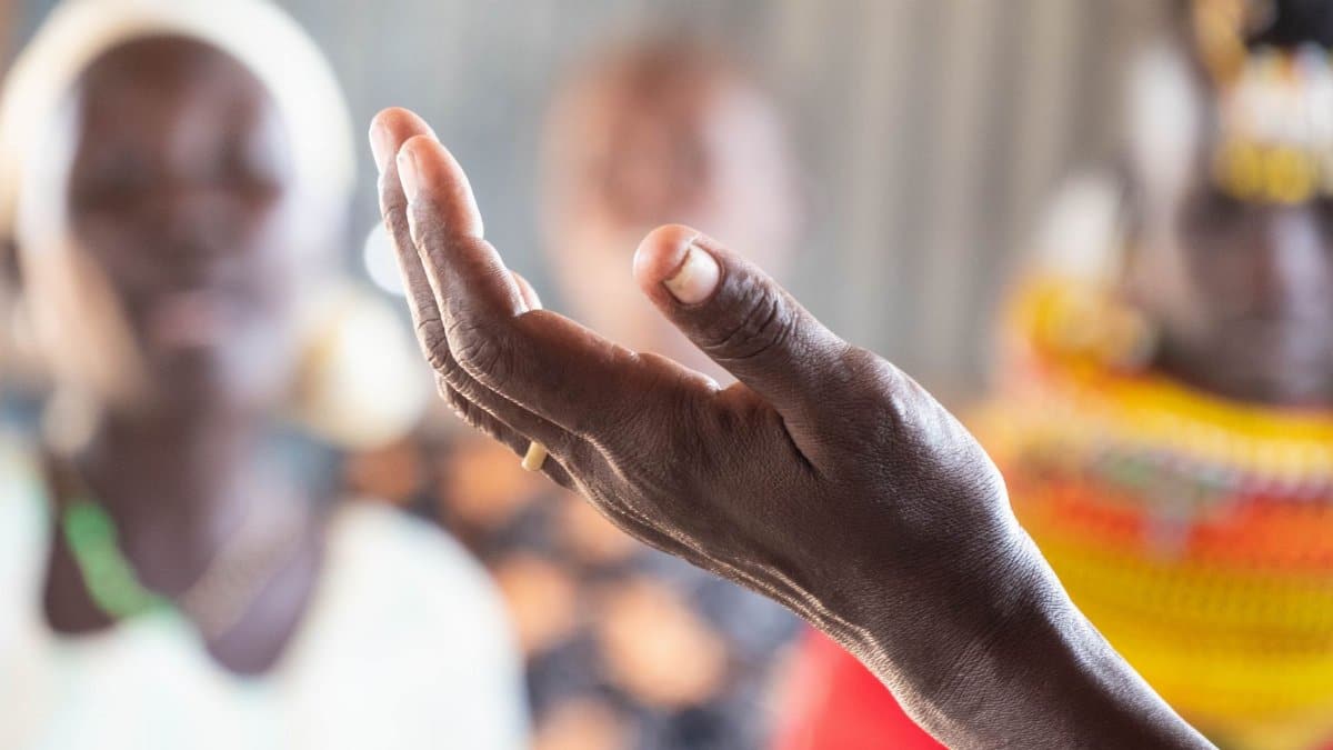 Detailed close-up of a hand with a ring, gesturing against a blurred background.