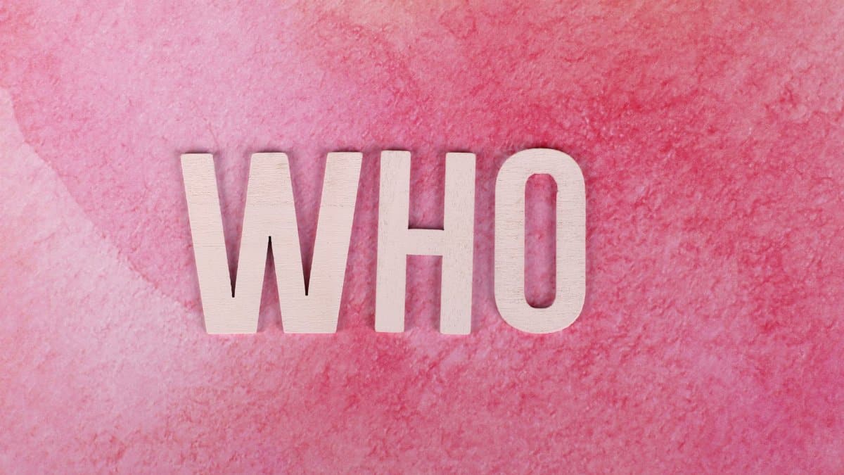 White wooden letters spelling 'WHO' on a textured pink background, offering ample copyspace.