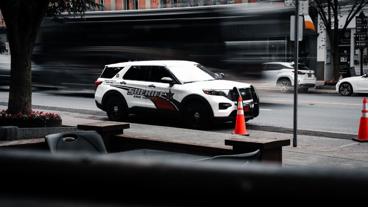 Sheriff's vehicle parked on a bustling city street with traffic motion blur.