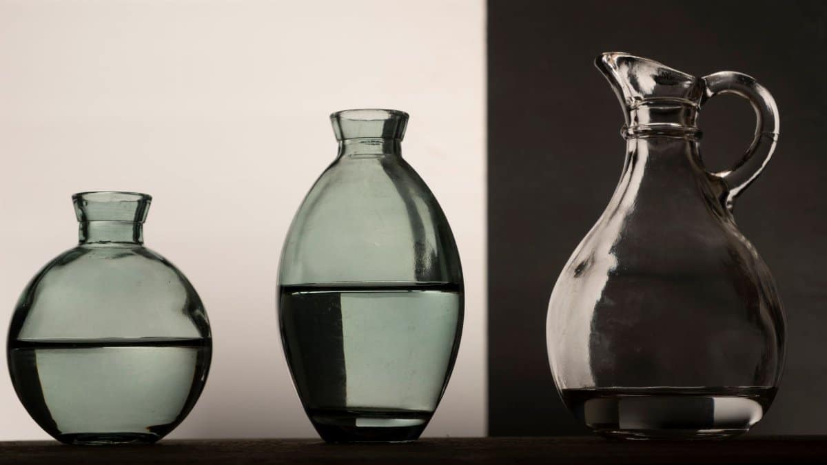 Stylized still life of glass vases and pitcher on a neutral background.