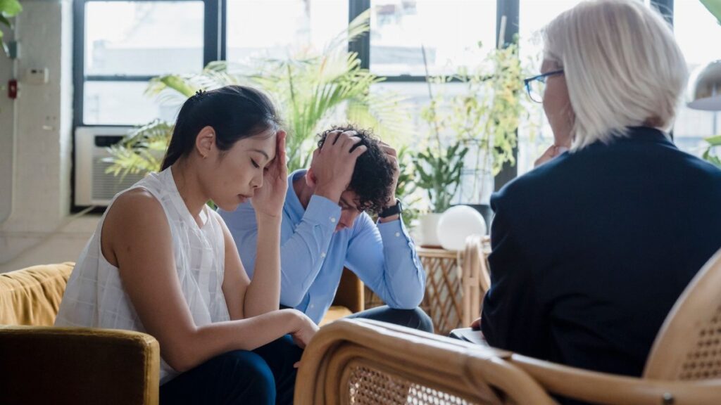 Young couple experiencing stress during a counseling session in a modern office setting.